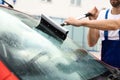 Man cleaning windshield with glass wiper, closeup
