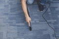 A man cleans the carpet flooring of an office with an upright vacuum cleaner with an attached extension wand