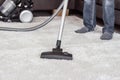 A man cleans the carpet with a vacuum cleaner. Royalty Free Stock Photo