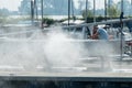 Man cleans catamaran with high-pressure sprayer in september sun