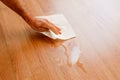 Man cleans a damp stain on the wooden floor of his house with absorbent kitchen paper