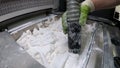 Man cleans details printed on industrial 3D printer from white plastic powder