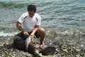 Man cleans fish he caught from the sea on shore