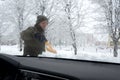 A man cleans frozen car brushes. View from the inside of the car through the windshield. Royalty Free Stock Photo