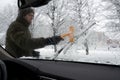 A man cleans frozen car brushes. View from the inside of the car through the windshield Royalty Free Stock Photo