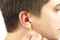 A man cleans his ears with a cotton swab, earwax. Body care concept Royalty Free Stock Photo