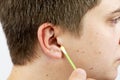 A man cleans his ears with a cotton swab, earwax. Body care concept Royalty Free Stock Photo