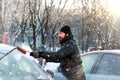 Man cleans snow from the glass at the car