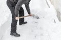 A man cleans snow shovel near the house