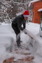 A man cleans steps from snow. In a red hat of Santa Claus and a leather black jacket. In felt boots. Clearing snow from the backya