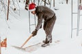 A man cleans steps from snow. In a red hat of Santa Claus and a leather black jacket. In felt boots. Clearing snow from the backya