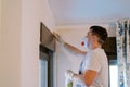 Man cleans the window frame with an antifungal spray. Side view