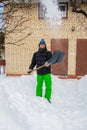 A man cleans the yard near his house of snow, sunny winter day Royalty Free Stock Photo