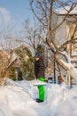 A man cleans the yard near his house of snow, sunny winter day Royalty Free Stock Photo