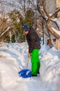 A man cleans the yard near his house of snow, sunny winter day Royalty Free Stock Photo