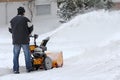 A man clears the road and the sidewalk with a snow blower Royalty Free Stock Photo