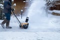 Man clears snow with a snow blower in house yard.