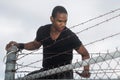 Man climbing over barbed wire fence Royalty Free Stock Photo