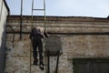 Man climbs ladder onto roof. Person climbs up stairs. Descent from roof Royalty Free Stock Photo