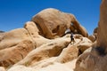 Man climbs through the rocks and boulders on Arch Rock Trail in Joshua Tree National Park, CA, USA. Travel concept Royalty Free Stock Photo