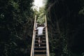 Man Climbs A Steep Flight Of Stairs Surrounded By Greenery In A Rainforest - Concept Of Adventure
