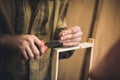 Man clogs a nail wooden frame for bees. Hands with long thin fingers hold wooden frame.