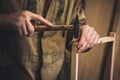 Man clogs a nail wooden frame for bees. Hands with long thin fingers hold wooden frame.