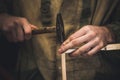 Man clogs a nail wooden frame for bees. Hands with long thin fingers hold wooden frame.