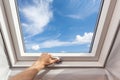 Man close new skylight mansard window in an attic room against blue sky. Royalty Free Stock Photo