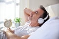 Man with closed eyes listening music lying in bed closeup