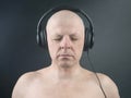 Man with closed eyes listens to music with headphones on dark background Royalty Free Stock Photo