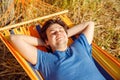 Man with closed eyes is resting in colorful hammock. Happy smiling young caucasian 34 years old man in blue t shirt, waist up Royalty Free Stock Photo