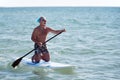 Man in clown mask paddleboarding Royalty Free Stock Photo