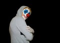 Man in a clown mask stands sideways on an isolated black background Royalty Free Stock Photo