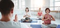 Man coach trains group of women yoga exercises for maintaining health care in white class. People together practis yoga poses Royalty Free Stock Photo