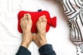 Man with Cold feet in bed on a red hot water bottle