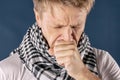 Man with cold and flu illness suffering from a headache and cough. Blue background Royalty Free Stock Photo