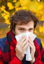 Man with cold rhinitis on autumn background. Fall flu season. Il Royalty Free Stock Photo