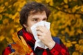 Man with cold rhinitis on autumn background. Fall flu season. Il