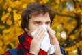 Man with cold rhinitis on autumn background. Fall flu season. Il