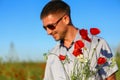 A man collects a bouquet of poppies in the field, soft focus on a bouquet of flowers