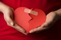 A man collects a broken red heart in his hands. red background . Concept of love and relationships