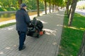 man collects garbage in bags on the sidewalk. The concept of cleaning the city park