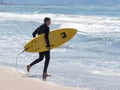 Man in color waterproof suit walks on beach with board