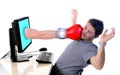 Man with computer hit by boxing glove Royalty Free Stock Photo