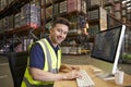 Man at computer in on-site warehouse office looks to camera Royalty Free Stock Photo