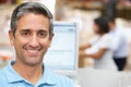 Man At Computer Terminal In Distribution Warehouse