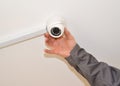 The man configures the surveillance camera on a room ceiling Royalty Free Stock Photo