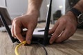 Man connecting cable to router at wooden table indoors, closeup. Wireless internet communication