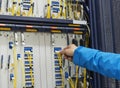 Man connecting network cables to switches in the computer room Royalty Free Stock Photo